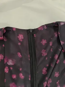 Detail of a deep V-neck floral dress showing back zipper and purple print fabric