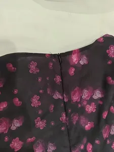 Detailed view of the invisible zipper and floral print on a black V-neck dress