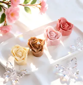 Detailed view of four multi-colored rose-shaped scented candles on a white tray