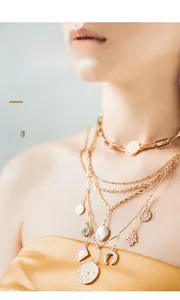 Detail of layered gold-plated necklaces with Bohemian charms and coin pendants