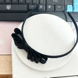 Detail view of the black triple-layered grosgrain ribbon bow on a slim headband