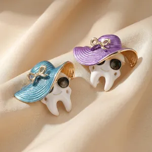 Creative enamel tooth brooches wearing hats and sunglasses on silk fabric background