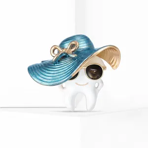Close-up of a cartoon tooth brooch wearing a blue gradient hat and golden sunglasses