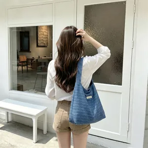 Detail of blue corduroy tote bag showing textured fabric and wide shoulder strap
