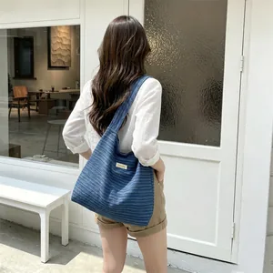 Close-up of deep blue textured tote bag with wide strap and rectangular fabric label