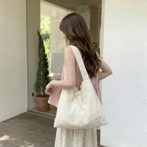 Detailed close-up of floral embroidery on off-white canvas tote bag with wide strap