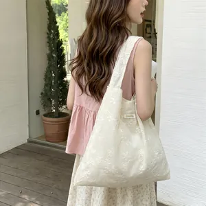Detail view of cream tote bag with floral embroidery and wide shoulder strap