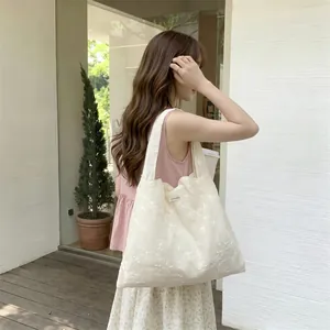 Detailed view of cream-colored lace embroidery and mesh fabric on a tote bag