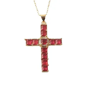 Adjustable gold cross necklace with ruby red cubic zirconia stones on white background