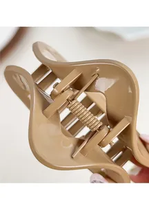 Detail view of large triangle shark clip featuring wavy edges and golden metal spring