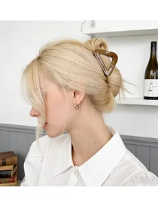Brown triangular hair claw clip worn by blonde model in a stylish lifestyle setting
