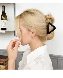 Detail view of a large black hollow triangular hair claw clip worn in a hair bun style
