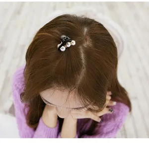 Elegant small pearl hair claw clip on brown hair showing stylish hair accessory use