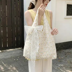 Detail of floral canvas tote bag with large white lace bow and yellow flower pattern