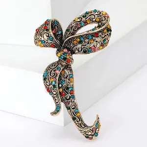 Close-up of vintage bow brooch with multi-colored rhinestones and gold filigree work