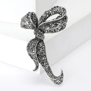 Macro shot of vintage silver bow brooch with black rhinestones on a white stand