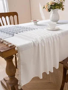 Close-up of beige woven tablecloth with grey herringbone pattern and tassel fringe edges