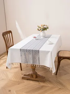 Detail of cream fabric tablecloth featuring a blue geometric runner and fringe edges