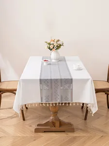 Macro detail of white tablecloth with grey geometric stripes and elegant fringe trim