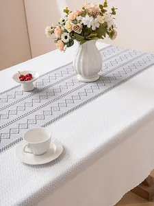 Detail of white fabric tablecloth featuring grey-blue geometric diamond pattern texture