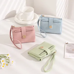 Three Morandi colored litchi grain purses with wrist straps in a soft lighting setting