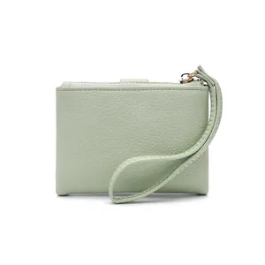 Detail of mint green pebble leather texture and gold zipper on a compact wristlet wallet