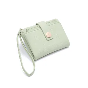 Close-up of mint green wallet featuring litchi texture, metal buckle and wrist strap