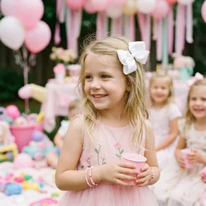 Détail du nœud de cheveux blanc en ruban gros-grain et bracelet perlé pour fille
