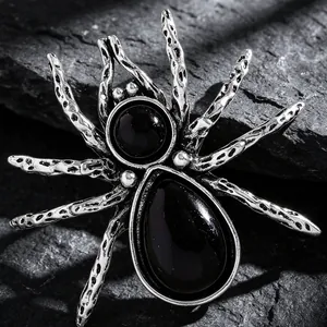 Macro shot of silver retro spider brooch with black gems on dark stone background