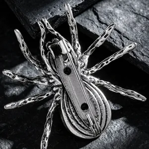 Macro view of silver spider brooch back showing secure pin safety clasp on dark rock