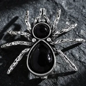 Detailed macro shot of a gothic silver spider brooch featuring black water-drop gemstones