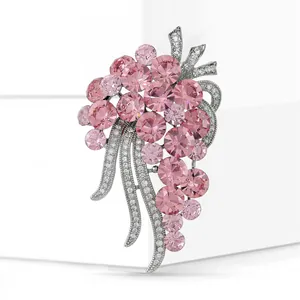 Macro shot of grape brooch with pink crystals and silver leaves on white pedestal