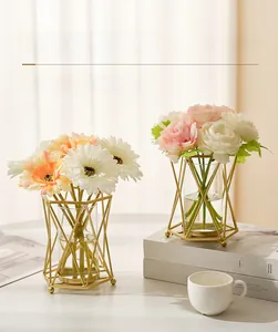 Gros plan d'un vase géométrique nordique en métal doré avec insert en verre et fleurs
