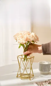 Détail de fleurs artificielles nordiques dans un vase en fer doré et verre