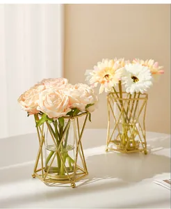 Détail du vase géométrique nordique en métal doré avec cylindre en verre et fleurs fraîches
