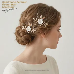 Close-up of handmade white ceramic flower hair pins with gold leaves on bridal hairstyle