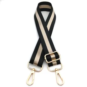 Detail of adjustable black and gold striped woven bag strap with golden metal lobster clasps