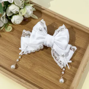 Détail d'une barrette nœud en satin blanc avec dentelle et glands en perles