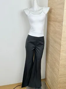 Detail view of high-waist black flare pants paired with a white slim fit camisole top