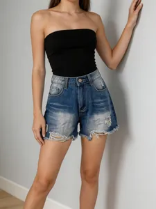 Close-up of blue denim shorts with distressed ripped holes and frayed raw hem edge