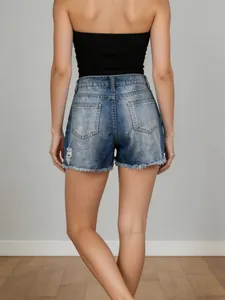 Women's distressed denim shorts in mid-blue with ripped fringe hem and back pockets