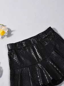 Close-up of black faux crocodile leather fabric and elastic waistband on fashion shorts