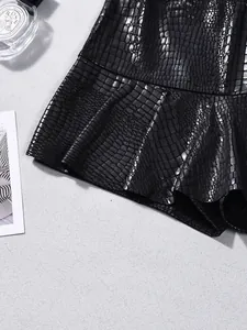 Close-up of black faux leather skirt with embossed crocodile texture and ruffle hem