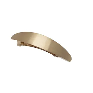 Matte gold minimalist metal hair clip with brushed texture and curved streamlined design