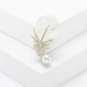 Detailed macro view of a golden feather brooch with mother-of-pearl and pearl accent