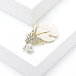 Elegant gold feather brooch with shimmering diamonds and white pearl for suit lapels