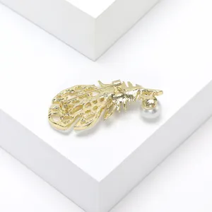 Elegant gold feather brooch with white pearl shown from a detailed back view