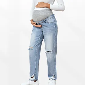Close-up of high-waist elastic belly support and ripped details on maternity jeans