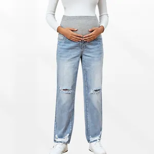 Detail of high-waist maternity jeans with elastic belly support and ripped knees