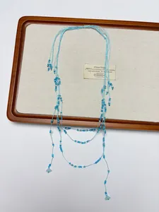 Detail of light blue handmade beaded necklace with bohemian fringe on canvas board